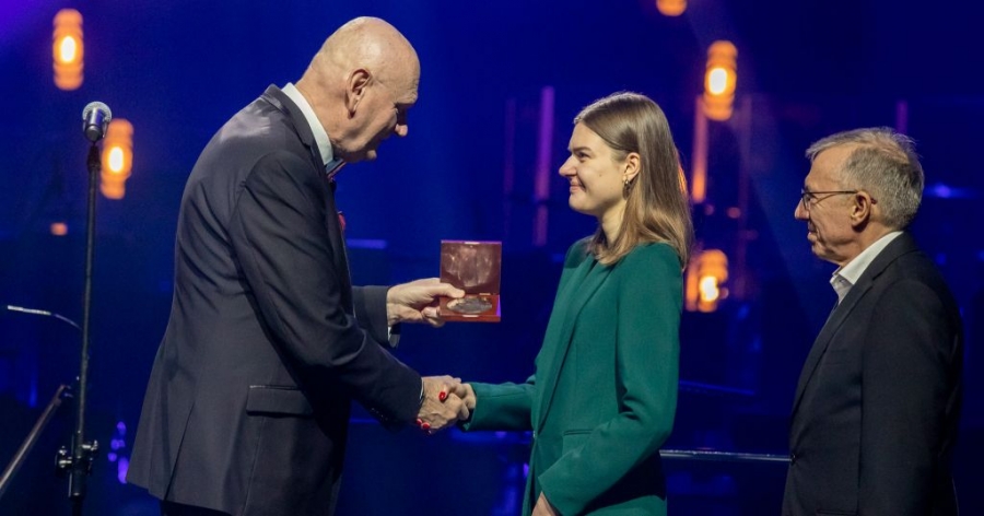 Prezydent Torunia wręcza studentce medal. Obok studentki stoi drugi wyróżniony