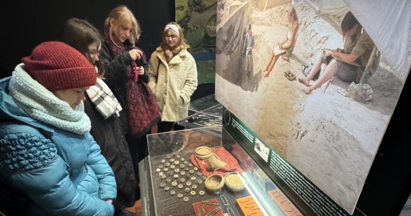 Grupa studentów stojąca przed gablotą z artefaktami archeologicznymi w muzemu