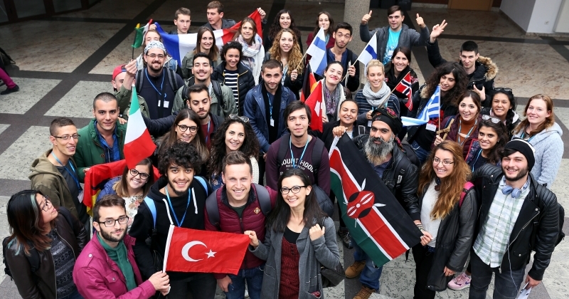 Grupa studentów z programu Erasmus z flagami.