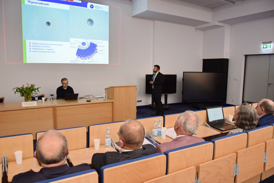 Prelegent obok swojej prezentacji ze wskaźnikiem w reku 