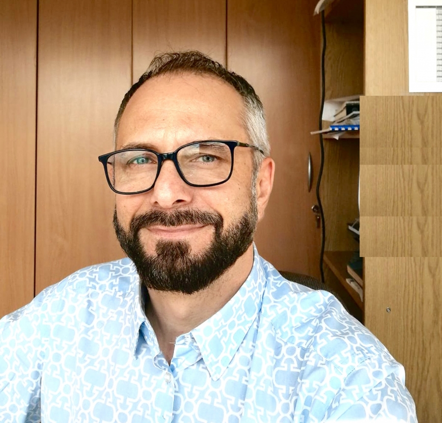 dr hab. Janusz Niedojadło, prof UMK w swojej pracowni, na tle regału z książkami