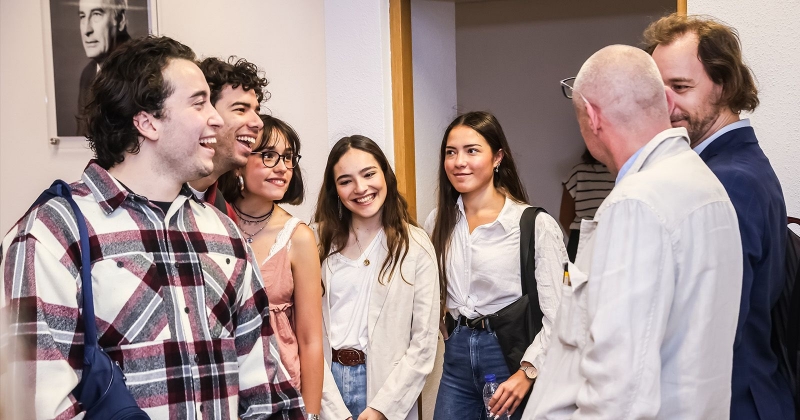 A group of people standing, talking with each other and laughing