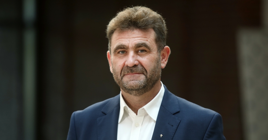 Zdjęcie portretowe ciemnowłosyego mężczyzny z brodą w garniturze 