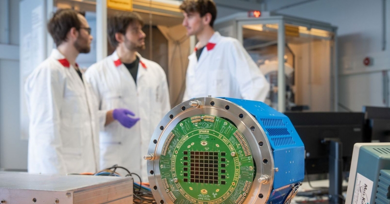 Three scientists stand in a lab. In the foreground you can see a device with colored sensors