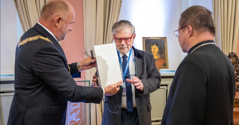 Marszałek województwa wręcza statuetkę prof. Weilerowi. Obok stoi kardynał Grzegorz Ryś, w tle portret Mikołaja Kopernika