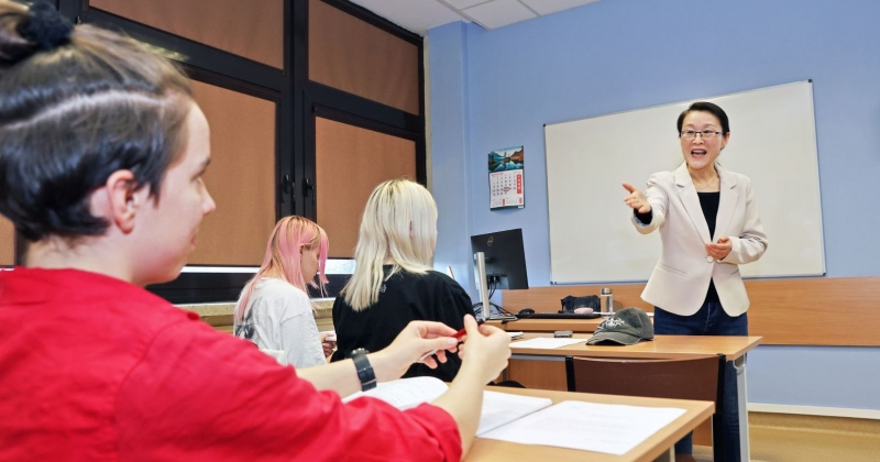 Zajęcia w sali dydaktycznej, wykładowczyni wskazuje na osobę, która udziela odpowiedzi
