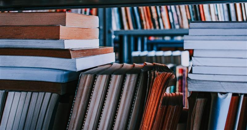 Stosy książek i czasopism na półkach bibliotecznych