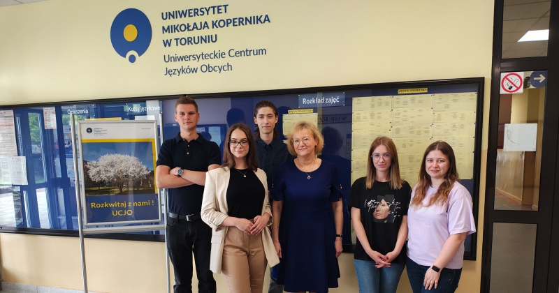 w holu głównym UCJO widoczni są tegoroczni laureaci Konkursu ? Mistrz Języka Specjalistycznego? ? studenci Wydziału Nauk Historycznych ( od lewej: Mikołaj Tański, Klaudia Banaś, Wojciech Jóźwiak; pośrodku stoi mgr Dorota Hoffmann, a na prawo od niej laureatki: Natalia Mytlewska i  Rita Skorupińska) wraz z wykładowcą j.angielskiego  - mgr Dorotą Hoffmann. 