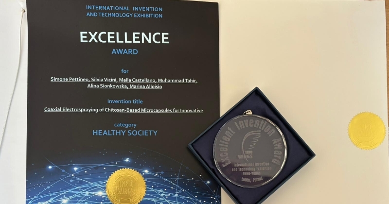 Certificate and medal awarded at the International Invention and Technology Exhibition. The certificate reads 'Excellence Award' in the Healthy Society category, given to Simone Pettineo, Silvia Vicini, Maila Castellano, Muhammad Tahir, Alina Sionkowska, and Marina Alloisio for the invention titled 'Coaxial Electrospraying of Chitosan-Based Microcapsules for Innovative.' A medal in a blue box is displayed next to the certificate, both bearing official gold seals.