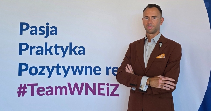 mężczyzna stojący na tle napisu: "Pasja, praktyka, pozytywne relacje"