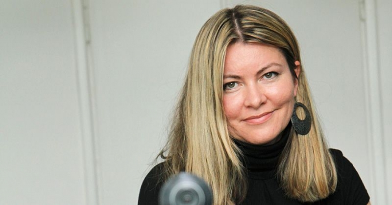 Professor Słabkowska - a woman with long blonde hair wearing a black top and round earrings smiles at the camera