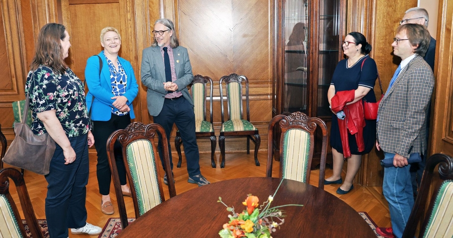 Six people stand in a semicircle in the historic interior of the Collegium Maximum building at Nicolaus