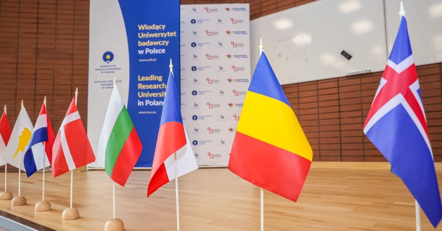 Małe flagi różnych krajów, a w tle rollup z logo UMK i napisem 