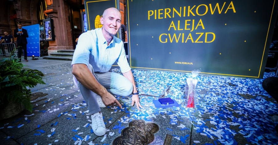 Mirosław Ziętarski kuca przy swojej Katarzynce i wskazuje na nią palcem, w tle napis 