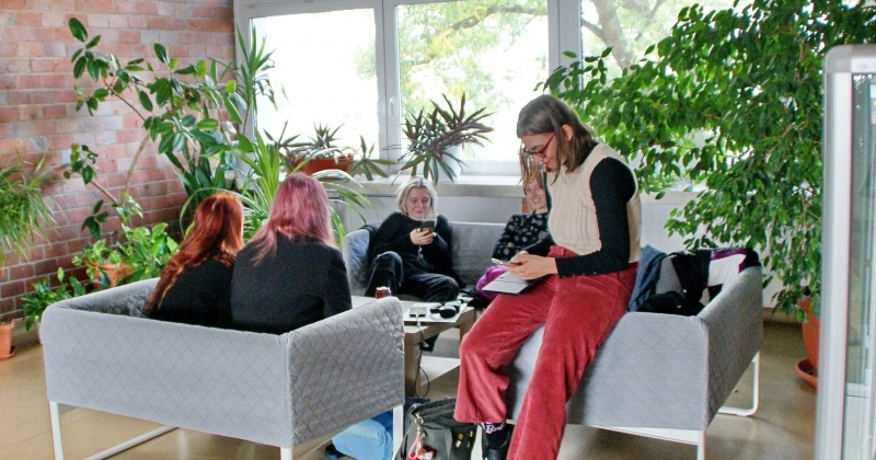 Grupa studentów siedząca na kanapie na WNBiW, w tle rośliny