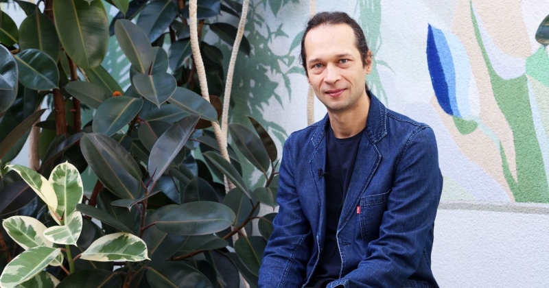 Portret prof. dr. hab Adama Izdebskiego zrobiony na tle roślin w Interdyscyplinarnym Centrum Nowoczesnych Technologii UMK