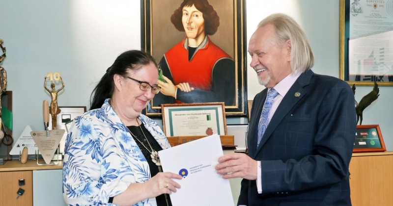 Rektor Andrzej Tretyn wręcza teczkę z powołaniem prof. Danucie Dziawgo. W tle portret Mikołaja Kopernika