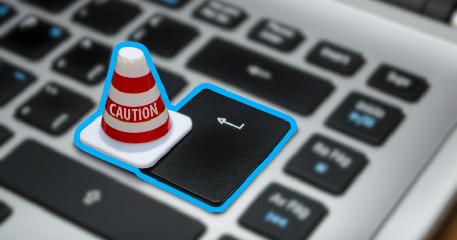 Klawiatura komputera. Na przycisku enter stoi miniaturowy stożek z napisem CAUTION.