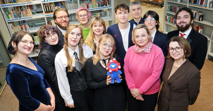 Grupa uśmiechniętych studentek i studentów patrzy w obiektyw, pozując do zdjęcia