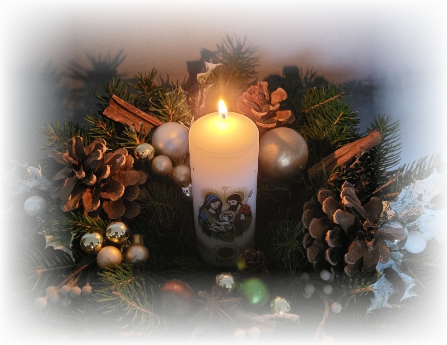 Stroik świąteczny z gałązek świerkowych, ozdobiony bombkami i szyszkami, z palącą się świecą pośrodku.