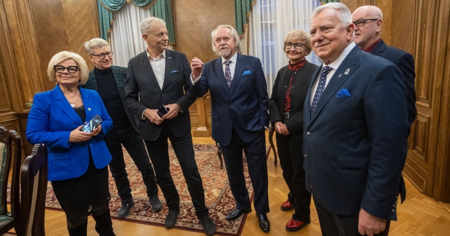 Rektor UMK stoi w towarzystwie Ambasadorek i Ambasadorów uczelni w reprezentacyjnych wnętrzach Collegium Maximum