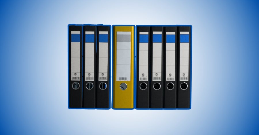 Kilka czarnych segregatorów i jeden żółty ustawione na ciemnoniebieskim tle.