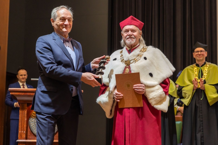 Kolegium rektorskie w uroczystych strojach (gronostaje) za stołem prezydialnym. w tle ekran z logo UMK i napsiem Święto Uniwersytetu 2026