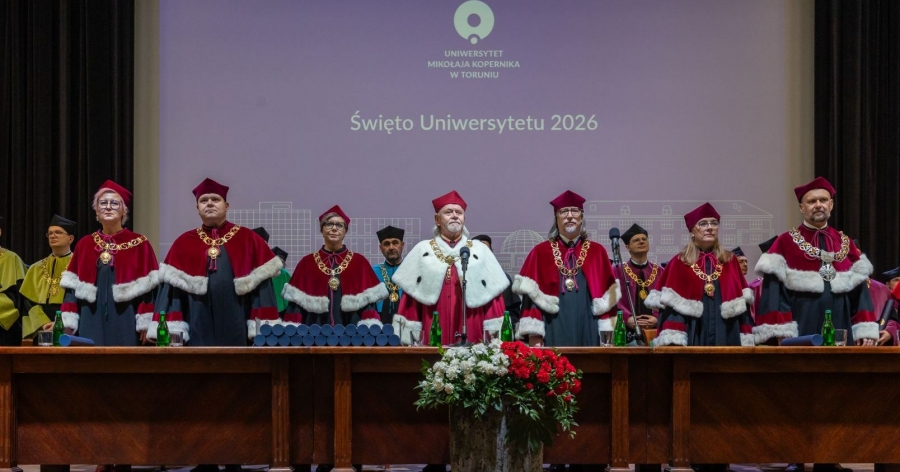 Kolegium rektorskie w uroczystych strojach (gronostaje) za stołem prezydialnym. w tle ekran z logo UMK i napsiem Święto Uniwersytetu 2026