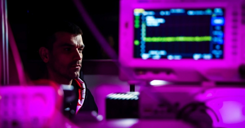 Professor Piotr Wcisło is sitting in a laboratory in a pink glow