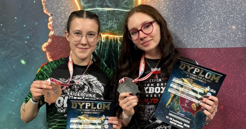 Dwie zawodniczki z uśmiechem prezentują brązowe medale i dyplomy zdobyte podczas Mistrzostw Polski w Kickboxingu.