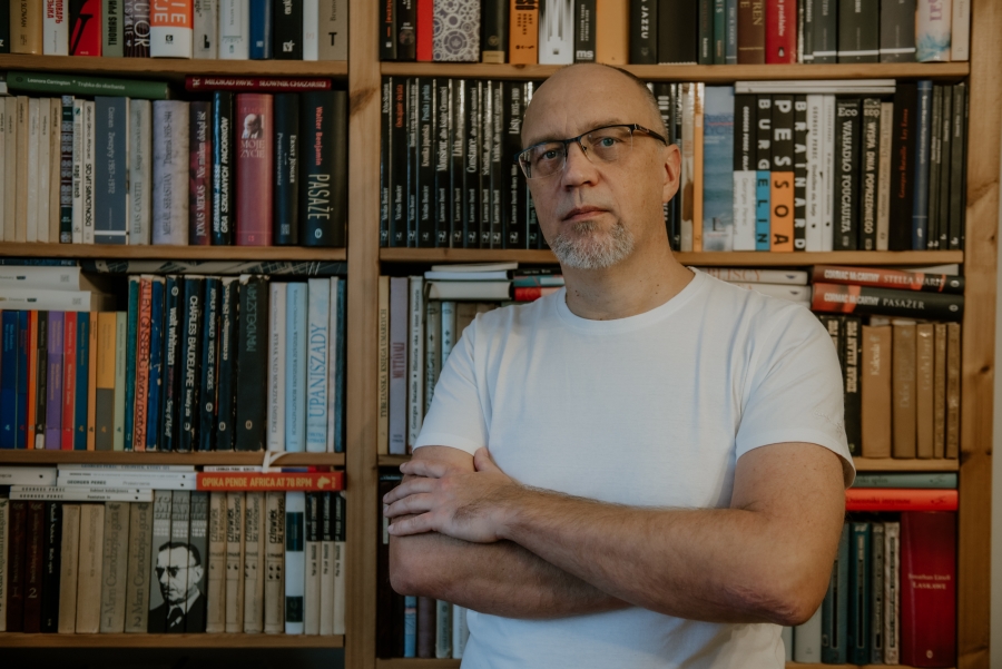 prof. dr hab. Dariusz Brzostek, zdjęcie portretowe na tle książek