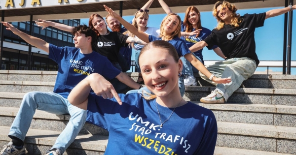 Osoby studiujące w koszulkach z napisem stąd trafisz wszędzie siedzą na schodach przed rektoratem i rozkładają szeroko ramiona, jakby przygotowywały się do lotu