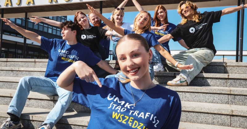 Osoby studiujące w koszulkach z napisem stąd trafisz wszędzie siedzą na schodach przed rektoratem i rozkładają szeroko ramiona, jakby przygotowywały się do lotu