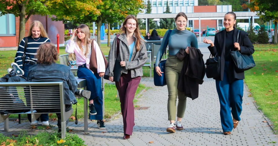 Kilka osób studiujących idzie przez kampus UMK